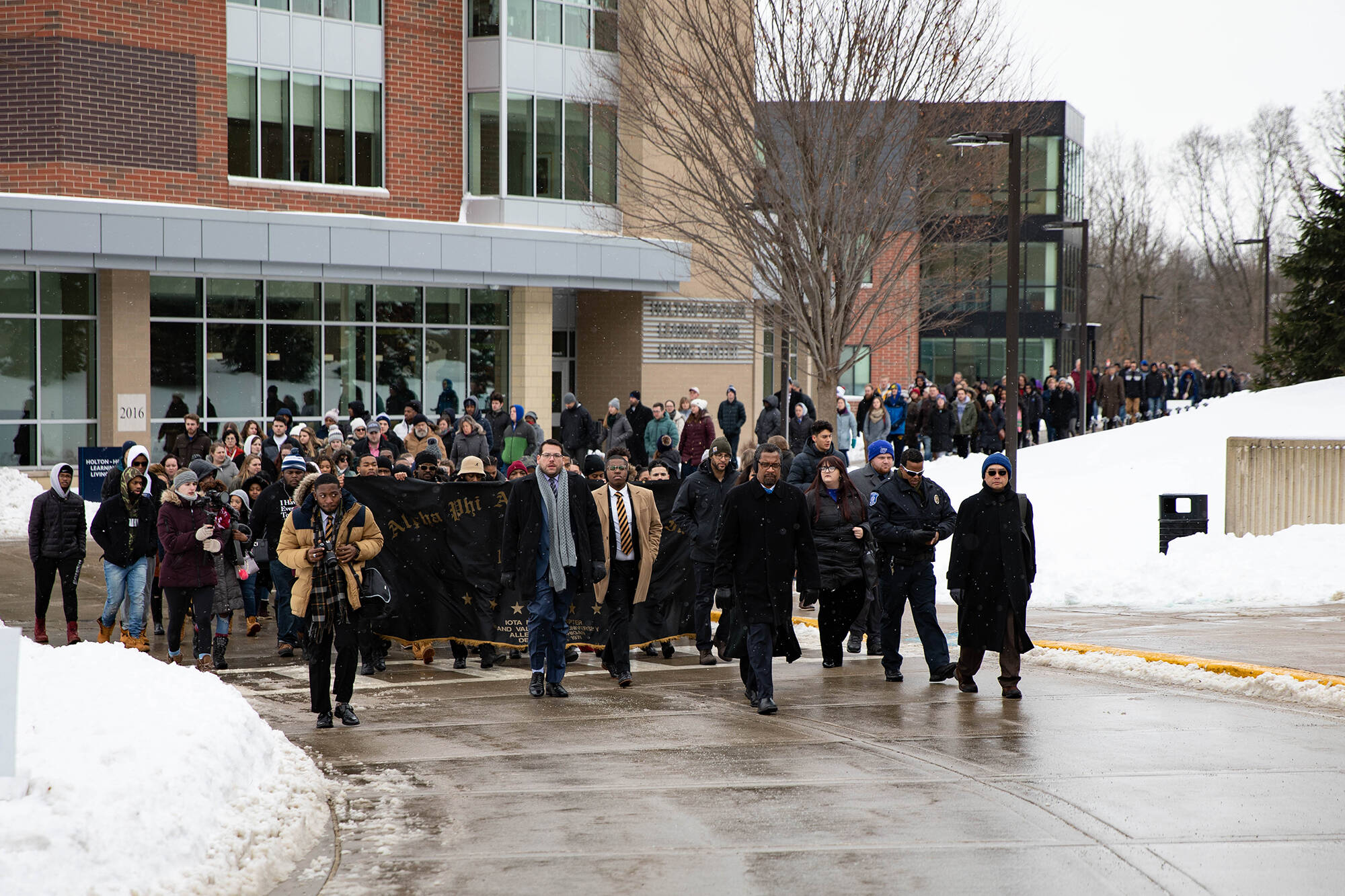 people marching on Allendale campus, snow on ground